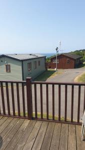 a wooden deck with a bench and a house at Holiday Lodge, sleeps 4, with sea & countryside views in Ore