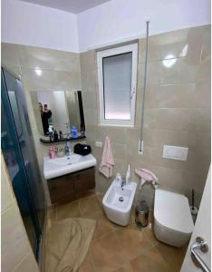 La salle de bains est pourvue d'un lavabo, de toilettes et d'un miroir. dans l'établissement Lungo mare holiday apartment for family, à Vlorë