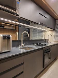 uma cozinha com um lavatório e um fogão em Lindo Apartamento a 1 Quadra da rua Coberta em Gramado