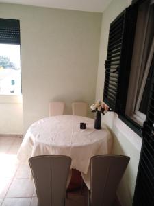 a white table with chairs and a vase of flowers on it at Apartman Ozi in Petrovac na Moru