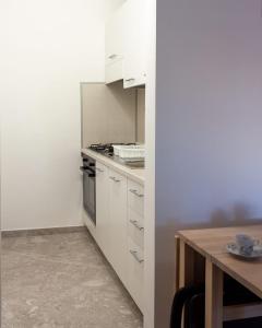 a kitchen with white cabinets and a wooden table at Nopal casa vacanze in San Vito dei Normanni