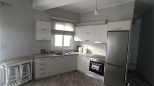 a kitchen with white cabinets and a stainless steel refrigerator at AKTI Apartment in Agios Kirykos
