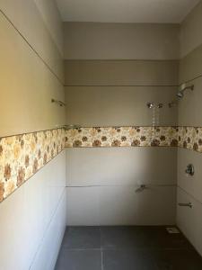 baño con ducha y azulejos en la pared en ASMA en Ahmedabad