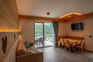 a living room with a couch and a table with chairs at Dolomites Chalet Wolf in Molveno