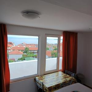 een kamer met een raam met een tafel en uitzicht bij Guest House Olimpiya in Sveti Vlas