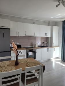 a kitchen with white cabinets and a table with a vase on it at Amparo in Satu Mare