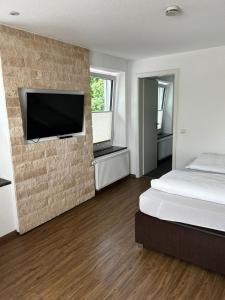 a bedroom with a bed and a flat screen tv on a brick wall at Alte Schmiede - XXL Foodhouse in Kempten