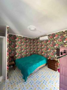 a bedroom with a green bed and floral wallpaper at Tenuta Balabaia, Townhouse. in Caccamo