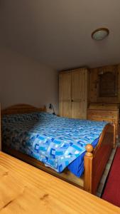 1 dormitorio con 1 cama con sábanas azules y armarios de madera en La Cleyva, en Valpelline