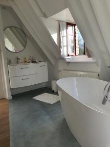 La salle de bains est pourvue d'une baignoire blanche et d'un lavabo. dans l'établissement La Grange du Moulin de Lossulien, à Le Relecq-Kerhuon