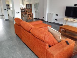 un sofá naranja en la sala de estar con TV en Casa San Miguel 93 santander, en Santander