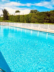 une grande piscine d'eau bleue avec une clôture blanche dans l'établissement Mandelieu Grand studio avec Piscine et proche de la Mer, à Mandelieu-la-Napoule