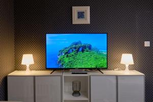 une télévision à écran plat assise sur une armoire avec deux lampes dans l'établissement Joy City Stay Versului 8, à Timişoara