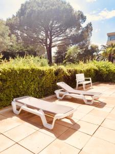 - 2 lits blancs et une chaise sur la terrasse dans l'établissement Mandelieu Grand studio avec Piscine et proche de la Mer, à Mandelieu-la-Napoule