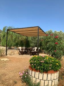 a picnic shelter with a table and benches and flowers at Villa Gloria Plataria in Igoumenitsa +14 photos