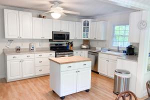uma cozinha com armários brancos e um forno com placa de fogão em Ravenswood Pool House em Sawyer