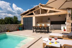 a house with a swimming pool and a table with wine glasses at villa du Passeron in Chambonas