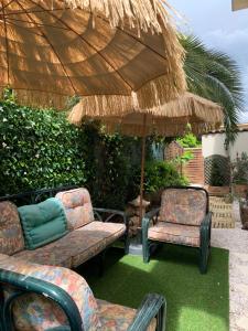a patio with two chairs and an umbrella at Hôtel La Villa des Oliviers in Cagnes-sur-Mer