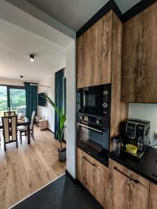 a kitchen with wooden cabinets and a living room at Domek Veron in Wysowa-Zdrój