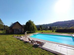 a swimming pool with chairs and a house at L'Herbe Haute in Honfleur