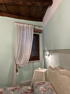 Schlafzimmer mit einem Bett, einem Tisch und einem Fenster in der Unterkunft ANTICA DIMORA DEL BORGO Luxury TUSCANY in Bibbiena