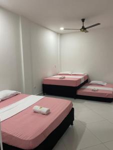 three beds in a room with pink and white at APARTAMENTO DORADAL in Doradal