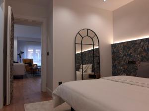 - une chambre avec un lit blanc et un miroir dans l'établissement Apartamento Nordeste, à Gijón