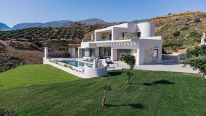 a large white house on top of a hill at Villa 7 Seas - With Amazing View in Lefkogeia