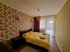 - une chambre avec un lit et un papier peint floral dans l'établissement Bougainvillea Apartman, à Sfântu-Gheorghe