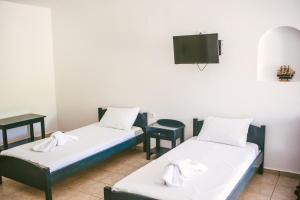 two beds in a room with a tv on the wall at Ο Μήλας in Agios Dimitrios
