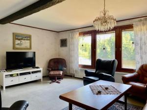 uma sala de estar com uma televisão, cadeiras e uma mesa em Holiday Home Småland Paradiset em Ryd