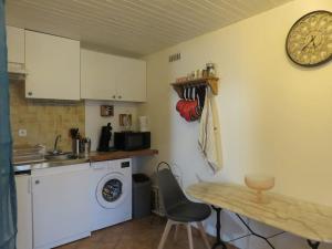 a kitchen with a washing machine and a table and a clock at Studio en rez de chaussée, avec jardin partagé. in Vars