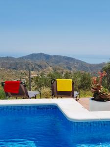 una piscina con 2 sillas junto a en En-suite bedroom with private entrance at Casa Sofija, en Sedella