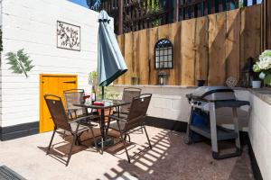 a table and chairs with a grill and an umbrella at The Snuggery a Cosy Country Cottage in Wellington