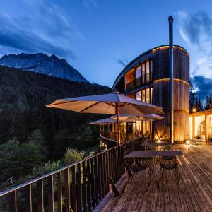 a building with tables and umbrellas on a deck at Hotel Arnica Scuol - Adults Only in Scuol
