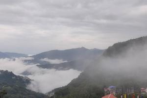 a view of a valley with clouds in the mountains at Shiloh Khim in Gangtok