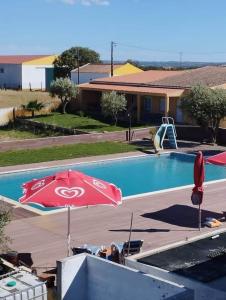 a swimming pool with a red umbrella and a playground at Nefama Pensao in Ourique