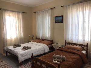 twee bedden in een slaapkamer met ramen en gordijnen bij GuestHouse Vrontos, close to Monemvasia 