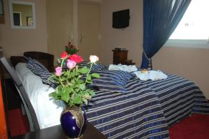 a bedroom with a bed with a vase with flowers on it at Ambassy Hotel in Kenitra