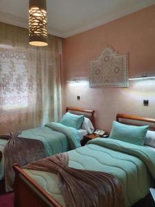 1 dormitorio con 2 camas y ventana en Ambassy Hotel en Kenitra