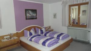 Schlafzimmer mit einem Bett mit lila und weißen Kissen in der Unterkunft Allgäuer Landhaus Stocker in Hopferau
