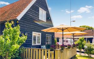 a blue house with a wooden fence and an umbrella at Lovely Home In Den Oever With Kitchen in Den Oever