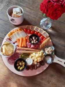 ein Teller mit Käse und anderen Lebensmitteln auf dem Tisch in der Unterkunft Au Charme de l'Eure in Villiers-le-Morhier