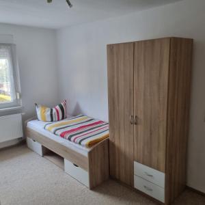 1 dormitorio con 1 cama y armario de madera en Appartmenthaus Zum Goldstern Monteurswohnung, en Staßfurt