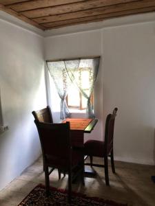 ein Esszimmer mit einem Tisch, Stühlen und einem Fenster in der Unterkunft Guesthouse Kujtimi in Theth