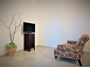 uma sala de estar com uma cadeira e uma televisão em Trullo Assiolo in Valle d'Itria em Martina Franca