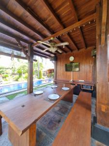 een grote houten tafel in een kamer met een zwembad bij Joglo Catu Villa in Singaraja