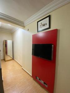 Pokój z czerwoną ścianą i telewizorem z płaskim ekranem w obiekcie Apartment D (Deluxe One Bedroom Apartment) w mieście Lagos