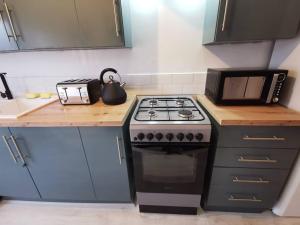 a kitchen with a stove and a microwave at Spacious 4 bed house, 7 Beds, Sofabed, Free Private Parking & Wifi in Birkenhead