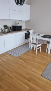 a kitchen with white cabinets and a wooden floor at Апартамент у моря in Tallinn